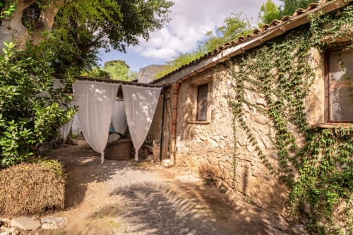 Stone cottage courtyard at Case Zucco B&B in Terrasini, Sicily with ivy-covered walls and white curtains
