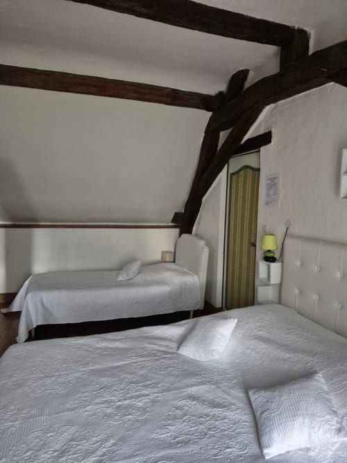 Spacieuse chambre familiale au Moulin Garnier avec poutres apparentes, deux lits aux draps blancs et mobilier d'époque à Vernou