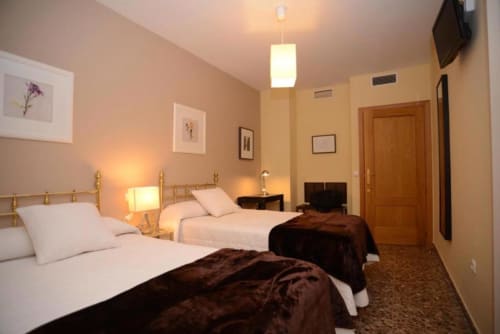 Habitación espaciosa de hotel en Mérida con camas gemelas, iluminación cálida y vista a la ciudad