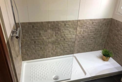 Moderno plato de ducha con paredes de azulejos grises y base blanca en apartamento de Mérida