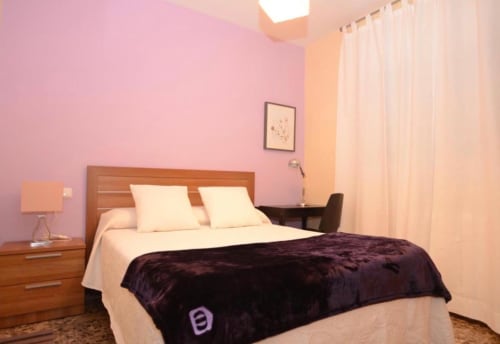 Acogedora habitación en apartamento Gestyp-AT en Mérida con paredes rosa, cama de madera y ropa de cama crema