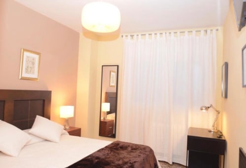 Dormitorio moderno en apartamento Gestyp-AT en Mérida con vista de la ciudad, cabecero de madera y decoración contemporánea