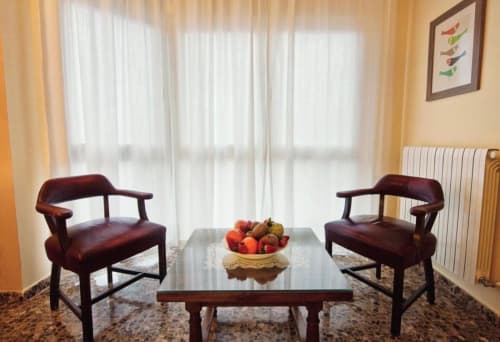 Elegante sala de estar moderna con sillones burdeos, mesa de cristal y frutero, hotel en Mérida con vistas a la ciudad