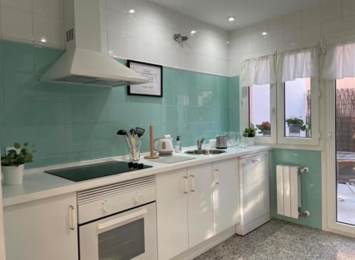 Cocina de cabaña moderna en tonos menta y blanco con vistas a la ciudad de Mérida, España