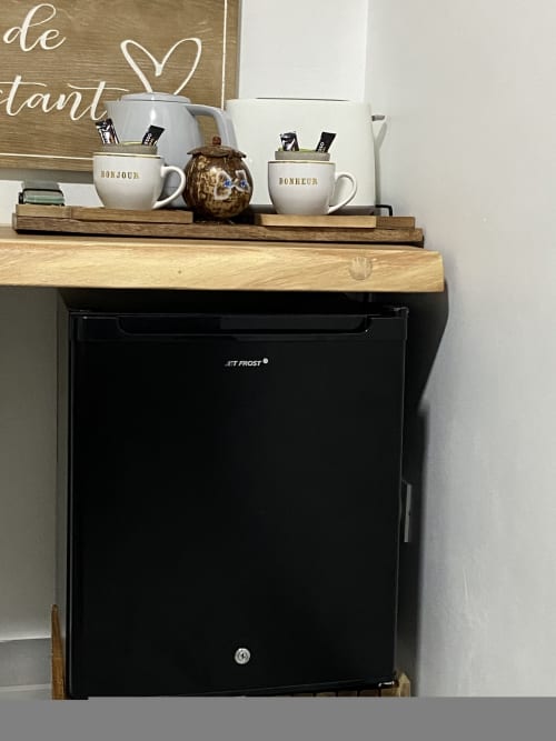 Mini frigo dans la chambre pour conserver vos boissons au frais, avec bouteille d'eau et jus offert.