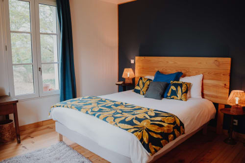 Spacious bedroom at Baccara Lodge in Arengosse with wooden bed, white linens, patterned throw, blue accent wall, and garden