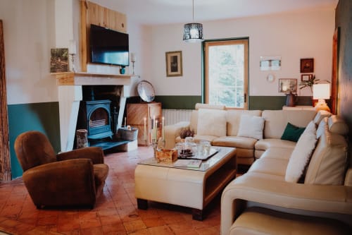 Baccara Lodge lounge with cream sectional, brown velvet chair, fireplace, and terracotta tiles in Arengosse