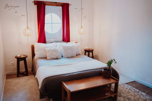 Cozy bedroom at Baccara Lodge B&B in Arengosse with bed, red curtains, pendant lights, and circular window