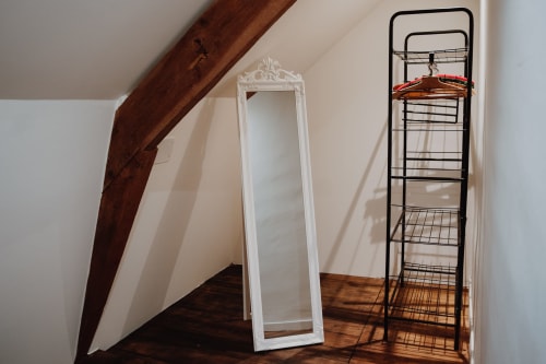 Attic bedroom at Baccara Lodge with white mirror, wooden beams, and metal storage shelf