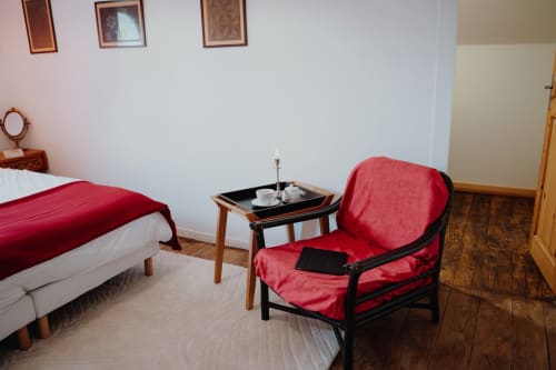 Cozy bedroom at Baccara Lodge guesthouse in Arengosse featuring red armchair, bed, and side table