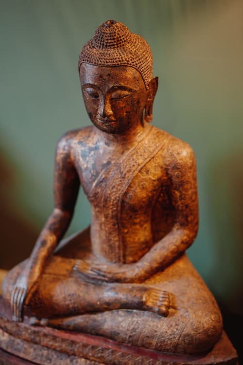 Wooden Buddha statue with intricate carvings at Baccara Lodge, Arengosse