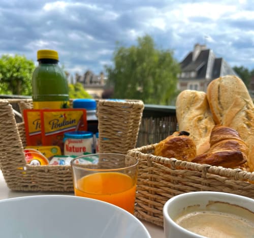 Continental breakfast spread overlooking Blois gardens with baguettes, juice, yogurt, and coffee at Locacharme cottage.