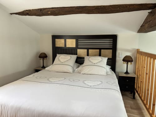 Chambre la Chouanne bedroom with exposed beam, black headboard, striped bedding, and garden view at Logis De La Bénétière,