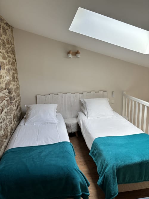 Twin beds with teal blankets in Suite du Meunier at Logis De La Bénétière, Treize-Vents, featuring skylight and stone wall