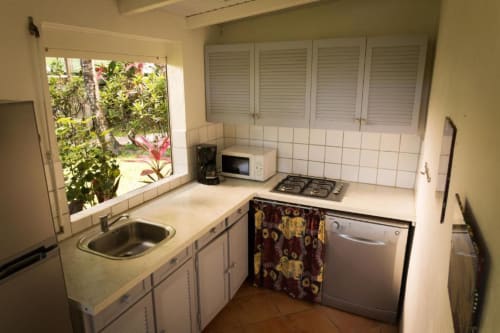 La cuisine du logement Mussaenda, gîte pour 4 à 6 personnes de la résidence de vacances Les Jardins de l'espérance à Bouillante, cuisine ouverte sur la végétation tropicale