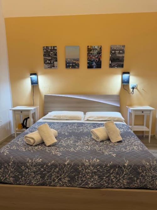 Camera matrimoniale moderna presso Bronze Horse Affittacamere a Firenze con testata decorata, comodini bianchi e vista città