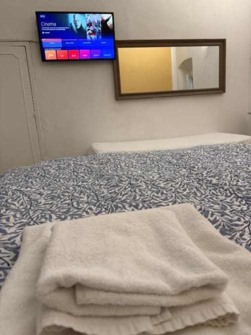 Camera d'hotel a Firenze con biancheria decorata, specchio incorniciato e TV da parete con menu Sky Cinema