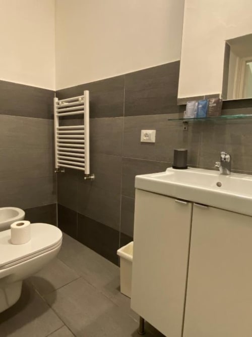 Bagno moderno della B&B di Firenze con lavandino bianco, toilet, scaldasalviette e pareti con piastrelle scure