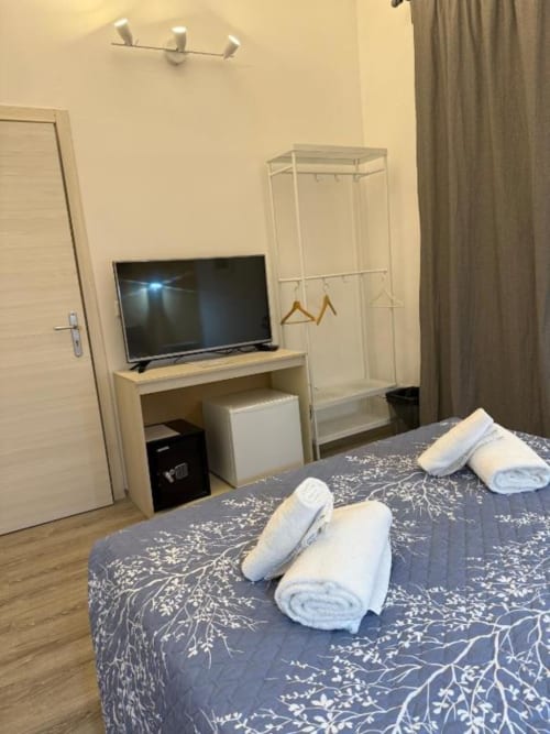 Spaziosa camera doppia al Bronze Horse Affittacamere Firenze con TV, armadio e asciugamani arrotolati sul letto