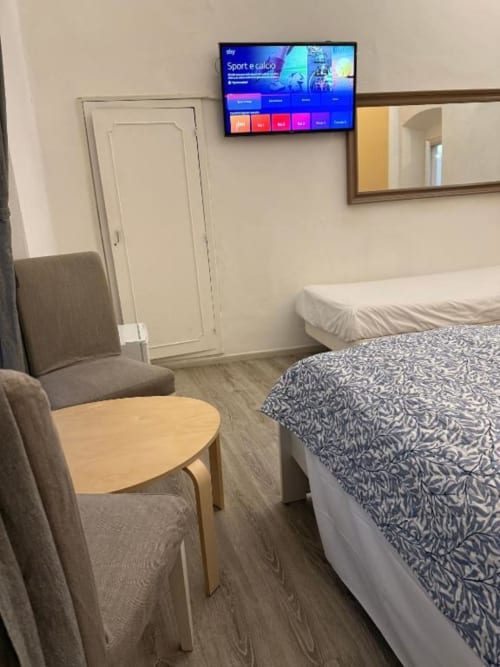 Luminosa camera tripla al Bronze Horse Firenze con letti gemelli, poltrona, tavolino, TV a parete e specchio nell'hotel di Firenze