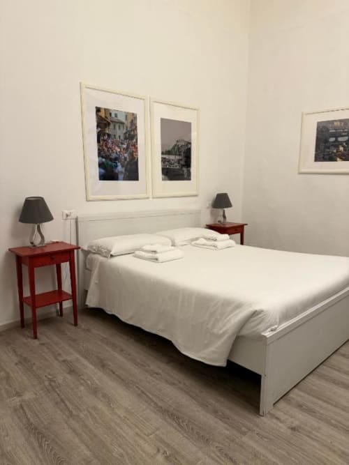 Elegante camera doppia superiore presso Bronze Horse Affittacamere a Firenze con letto bianco, comodini rossi e fotografie della città