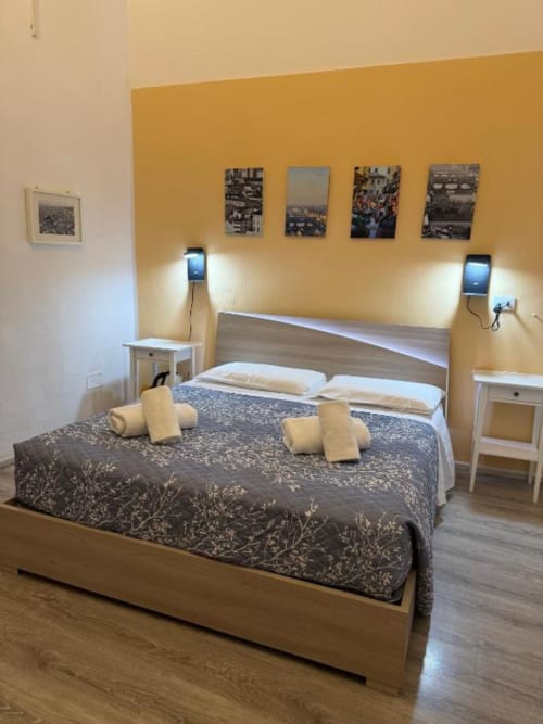 Camera da letto moderna al Bronze Horse Affittacamere di Firenze con parete in giallo, letto in legno e arredamento contemporaneo