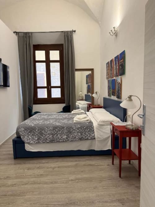 Camera da letto moderna al Bronze Horse Affittacamere di Firenze con letto blu, comodino rosso, vista sulla città e design contemporaneo