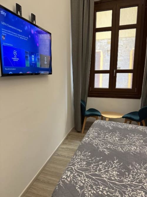 Camera doppia con letto, TV a muro che trasmette la UEFA Champions League, porta in legno scuro con vetri e dettagli blu