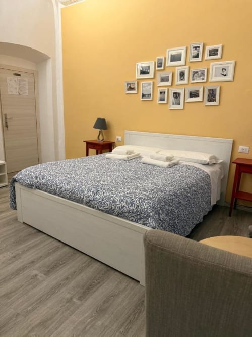 Camera da letto gialla brillante con letto bianco, coperta fantasia e parete galleriaall'hotel Bronze Horse Florence B&B
