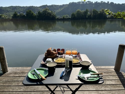 Breakfast table set for two on riverside dock overlooking Seine at Clairseine B&B, Tournedos-sur-Seine