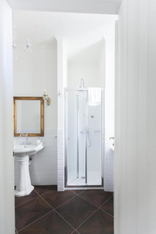 Modern bathroom in Suite 5 at Alessia's Place Como, featuring pedestal sink with framed mirror and glass shower enclosure on