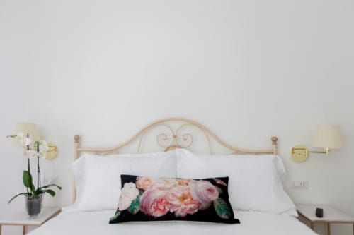 Elegant bedroom at Alessia's Place Como with wrought iron headboard, white linens, floral accent pillow, and brass bedside