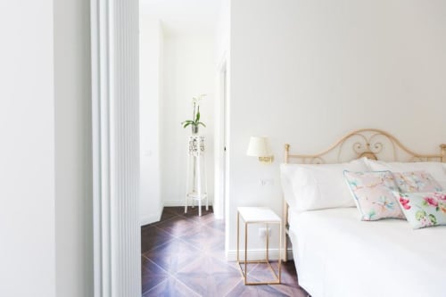 Bright bedroom at Alessia's Place Como B&B with elegant metal headboard, floral pillows, white bedding, and garden view