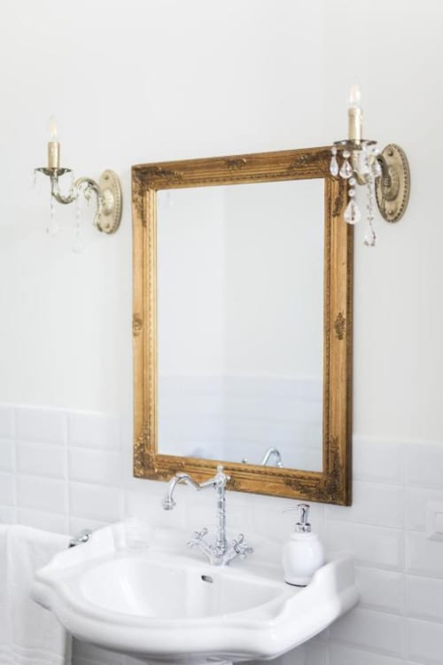 Elegant bathroom sink with ornate gold-framed mirror and crystal sconces at Alessia's Place B&B in Como