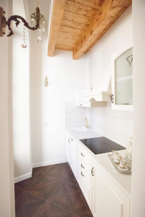 Cucina moderna nella Suite 3 di Alessia's Place, Como con mobili bianchi, lavello scuro, soffitto con travi in legno e specchio.