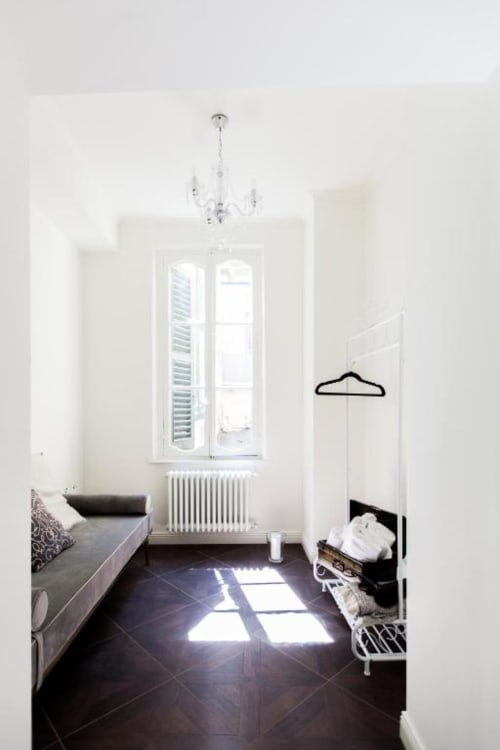 Bright bedroom at Alessia's Place Como with dark flooring, white walls, radiator, window, chandelier, and sofa seating area