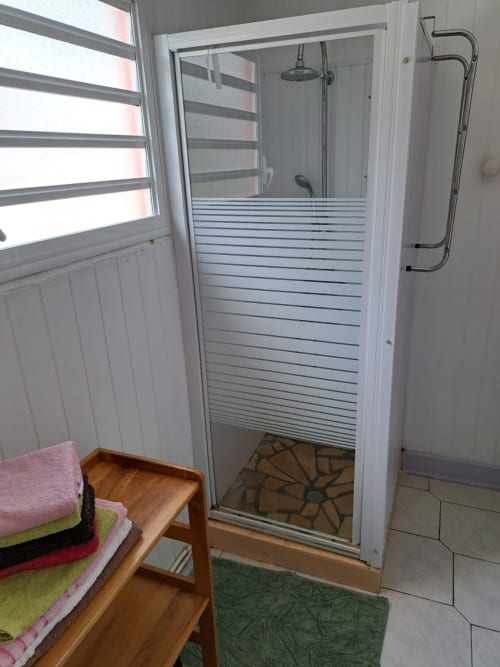 salle de bain du gîte Ixora avec douche, lavabo, toilette et lave linge. Pour des vacances réussies aux Jardins de Pointe Noire en Guadeloupe