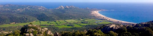 Paysage côtier avec vallées verdoyantes, collines boisées, plage de sable et mer Méditerranée bleue près de Vista D'oro en Monacia