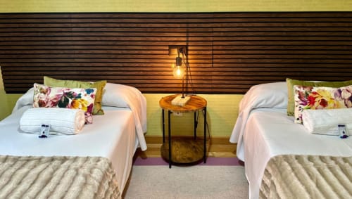 Habitación doble en Holibai Baiona con dos camas blancas, almohadas coloridas, mesilla de madera y cabecero de rayas moderno
