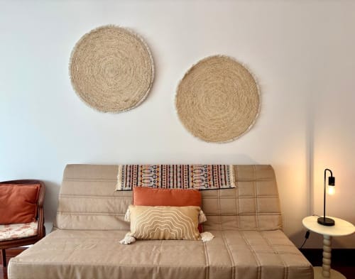 Sofá beige con cojines decorativos y tapices tejidos en la habitación del hotel Amieiro, Baiona