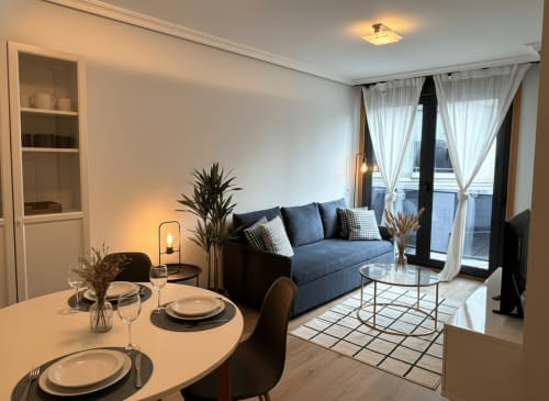 Moderno salón de apartamento con sofá azul, comedor y balcón en Baiona, España