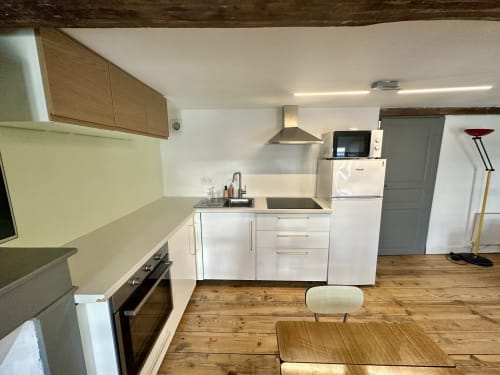 Nowoczesna kuchnia w apartamencie duplex w Lourdes z białymi szafkami, drewnianymi blatami, kuchenką i strefą jadalną