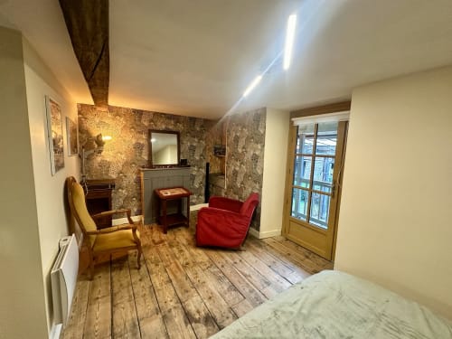Nowoczesny salon duplex w Lourdes z dekoracyjną tapetą, czerwonymi siedzeniami, drewnianymi podłogami i szklnymi drzwiami na balkon