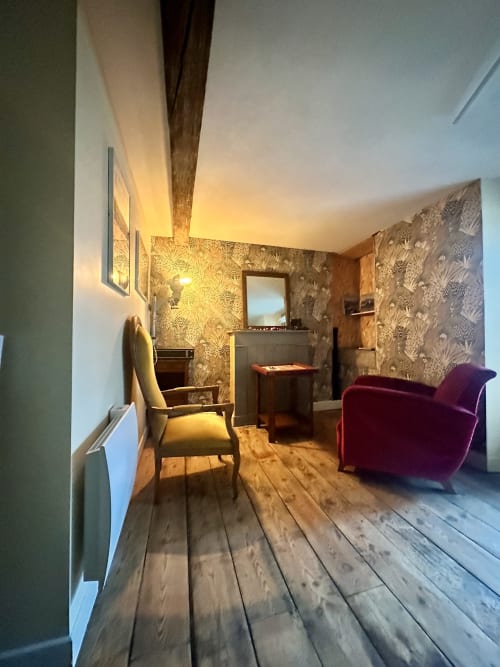 Elegancki salon duplex w Lourdes z drewnianymi podłogami, tapetą w wzory, burgundowymi meblami i ciepłym oświetleniem otoczenia
