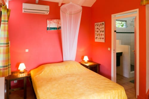 La chambre climatisée du gîte RoseCorail, dans la maison du haut des jardins de l'espérance à Bouillante en Guadeloupe, avec un lit de 160cm et moustiquaire