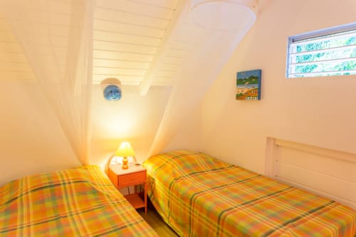 la mezzanine climatisée du logement RoseCorail aux jardins de l'espérance à Bouillante, avec 2 lits simples de 90cm, pour des nuits reposantes et fraîches