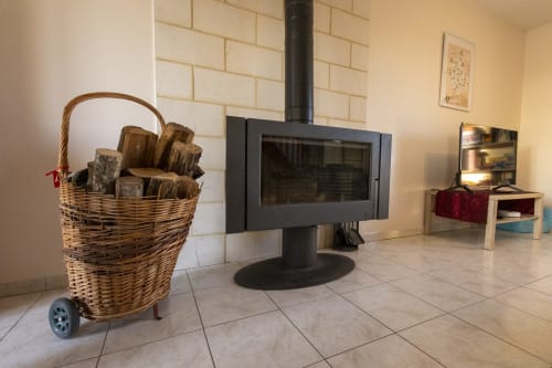 Intérieur cosy du gîte Accolade Châteaudun avec poêle à bois, panier de bois en osier et décoration vue jardin
