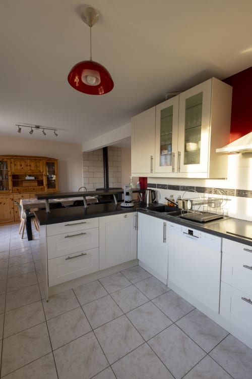 Cuisine moderne blanche avec plan de travail noir au gîte Accolade à Châteaudun, vue sur le jardin