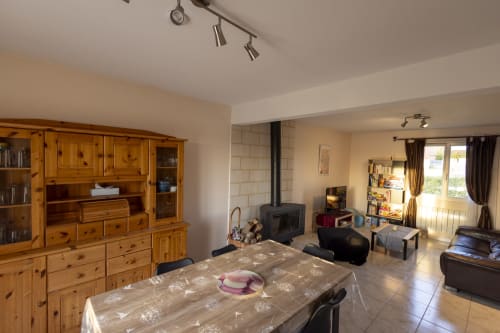 Séjour ouvert d'un cottage à Accolade Châteaudun avec mobilier en bois, poêle à bois et vue sur le jardin