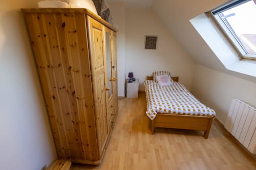 Chambre douillette sous les toits du gîte Accolade à Châteaudun, avec mobilier en bois et puit de lumière